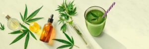 Panoramic flat lay of green cannabis smoothie and CBD oil bottles